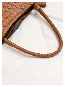 Detailed view of brown woven tote bag featuring an Intrecciato pattern and knot handle