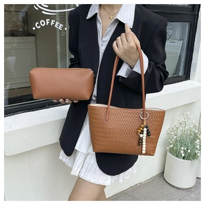 Detail of brown woven tote bag set with beaded tassel shown in outdoor lifestyle setting