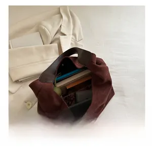 Detailed view of spacious burgundy suede tote bag showing capacity for books and umbrella