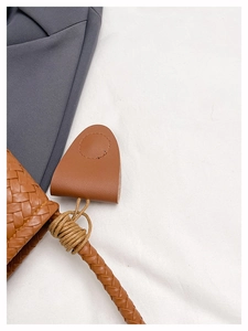 Macro detail of brown woven leather texture and precise stitching on the shoulder handbag