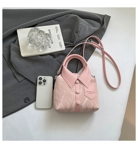 Pink shirt-shaped handbag with button detail and marble texture next to a smartphone