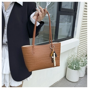 Detailed view of caramel woven leather tote bag with retro wood bead pendant charm