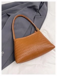 Detail of brown woven tote bag featuring intricate texture and hand-woven shoulder strap