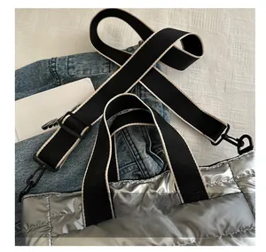 Detail of silver quilted tote bag featuring wide black and white striped webbing strap