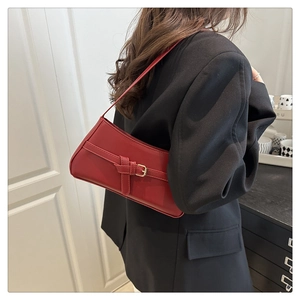 Detail of burgundy leather underarm bag with a golden metal buckle and minimalist strap