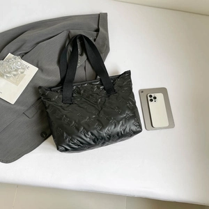 Large black quilted tote bag with bow patterns and durable woven handles for daily commute