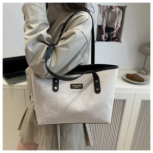 Detail of canvas tote bag with black leather straps and brand logo patch for daily commute