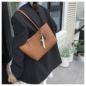 Brown woven tote bag detail showing leather texture and decorative bead charm