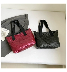 Close-up of shiny quilted tote bags with embossed bear patterns in burgundy and black