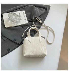 Detail of cream-colored wrinkled leather handbag with top handle and silver metal hardware