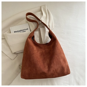 Close-up of caramel suede hobo bag with wide strap on minimalist cream background