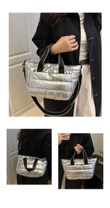 Macro shot of silver quilted puffer tote bag with black and white woven straps
