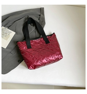 Detail of metallic wine red quilted tote bag with embossed bow texture and black strap