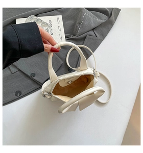 Top view of cream bucket bag showing inner lining, adjustable strap, and metal snap button