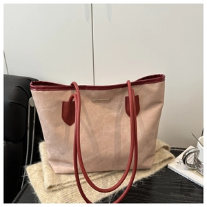 Détail du cabas en daim rose avec poignées en cuir bordeaux et barre dorée élégante