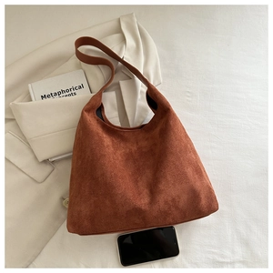 Detail view of large dark caramel suede tote bag shown with an urban lifestyle setting