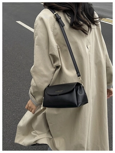 Scatto street style di una borsa a tracolla in pelle nera con scritte dorate alla moda
