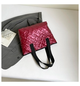 Detail of glossy magenta quilted tote bag with embossed patterns and black handles