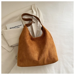Close-up of caramel suede tote bag texture with wide shoulder strap on beige blazer