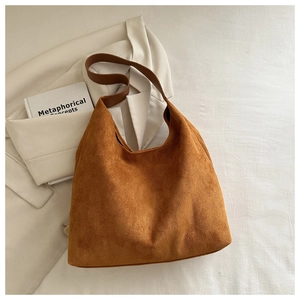 Macro detail of caramel suede tote bag texture with minimalist broad shoulder strap