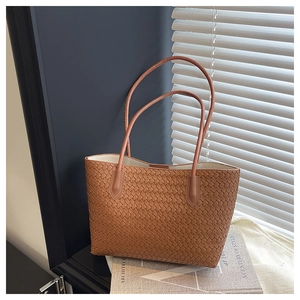 Close-up of brown woven tote bag with fine texture and slim handles in natural light