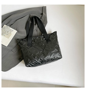 Detailed close-up of a black padded tote bag with quilted bow texture on white surface