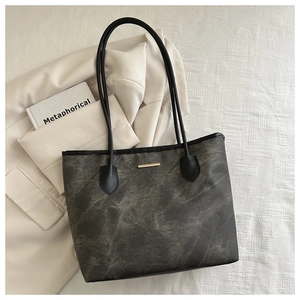 Gros plan d'un sac cabas gris vintage avec garniture dorée et anses en cuir