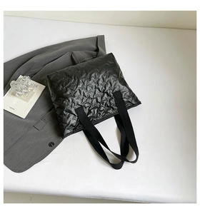 Detailed close-up of black quilted tote bag featuring elegant butterfly embossed texture