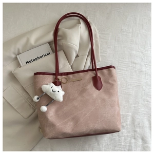 Détail d'un sac cabas rose poudré avec anses rouges et un charm en peluche blanche