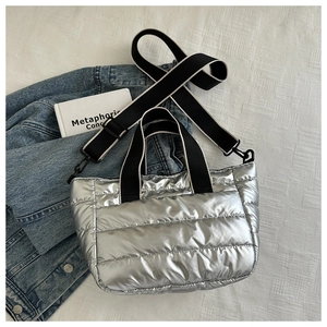 Detail of silver quilted bucket bag featuring metallic texture and striped woven handle
