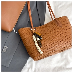 Nahaufnahme der geflochtenen Ledertasche mit Perlenanhänger und hochwertiger Metallbeschläge