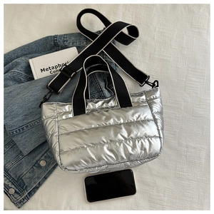 Detailed macro view of metallic silver quilted tote bag with striped webbing handles and strap