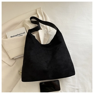 Detail of minimalist black hobo bag in matte suede texture shown with lifestyle props