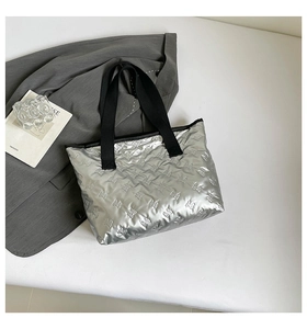 Detailed top view of silver quilted tote bag with bow texture and black canvas handles