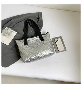 Close-up of silver quilted tote bag with butterfly patterns and black woven handles