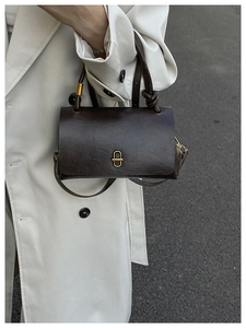 Close-up of deep brown leather bag with gold buckle and natural crinkle texture