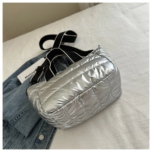 Detail of silver quilted puffer tote bag featuring a striped adjustable canvas strap