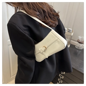 Detail of cream underarm bag showing adjustable strap and golden hardware on model