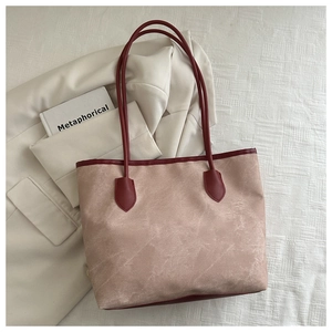 Vue détaillée du grand sac cabas rose poudré avec anses rouge foncé sur fond en tissu