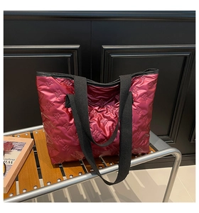 Detail of metallic rose pink tote bag with bow relief texture and black fabric handles
