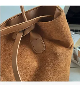 Detailed view of brown faux suede texture and leather handle on a vintage bucket bag