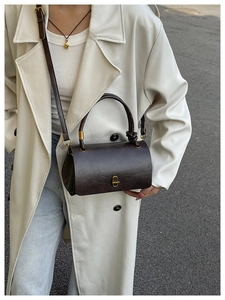 Detail of vintage dark brown cylinder bag with gold metallic lock on street model