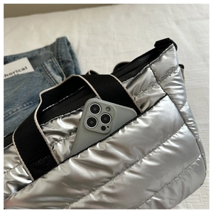 Close-up of silver quilted puffer bag interior with smartphone showing spacious capacity
