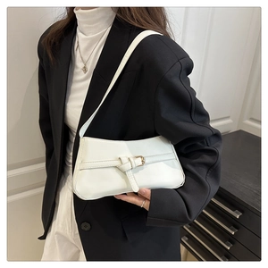 Detail of white underarm bag with knotted strap and gold buckle on black blazer