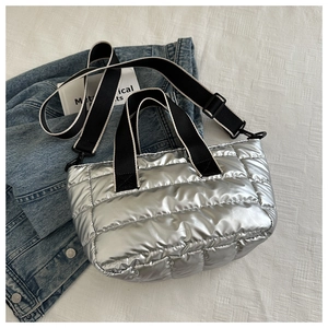 Detail of silver metallic quilted tote bag with texture and adjustable strap on denim