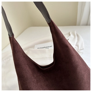 Close-up of the textured dark brown suede material and leather strap stitching on tote bag