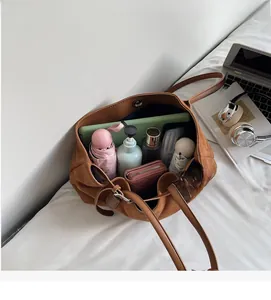 Spacious interior of brown suede tote bag showing tablet, wallet, and essentials