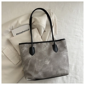 Détail du grand sac cabas à motif marbré sur un blazer blanc pour un look de bureau chic