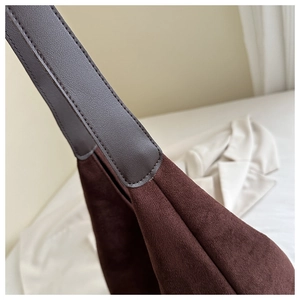 Detail showing the seamless leather strap stitching on a dark brown suede tote bag