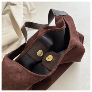 Detail of gold magnetic clasp and suede texture on brown large-capacity tote bag
